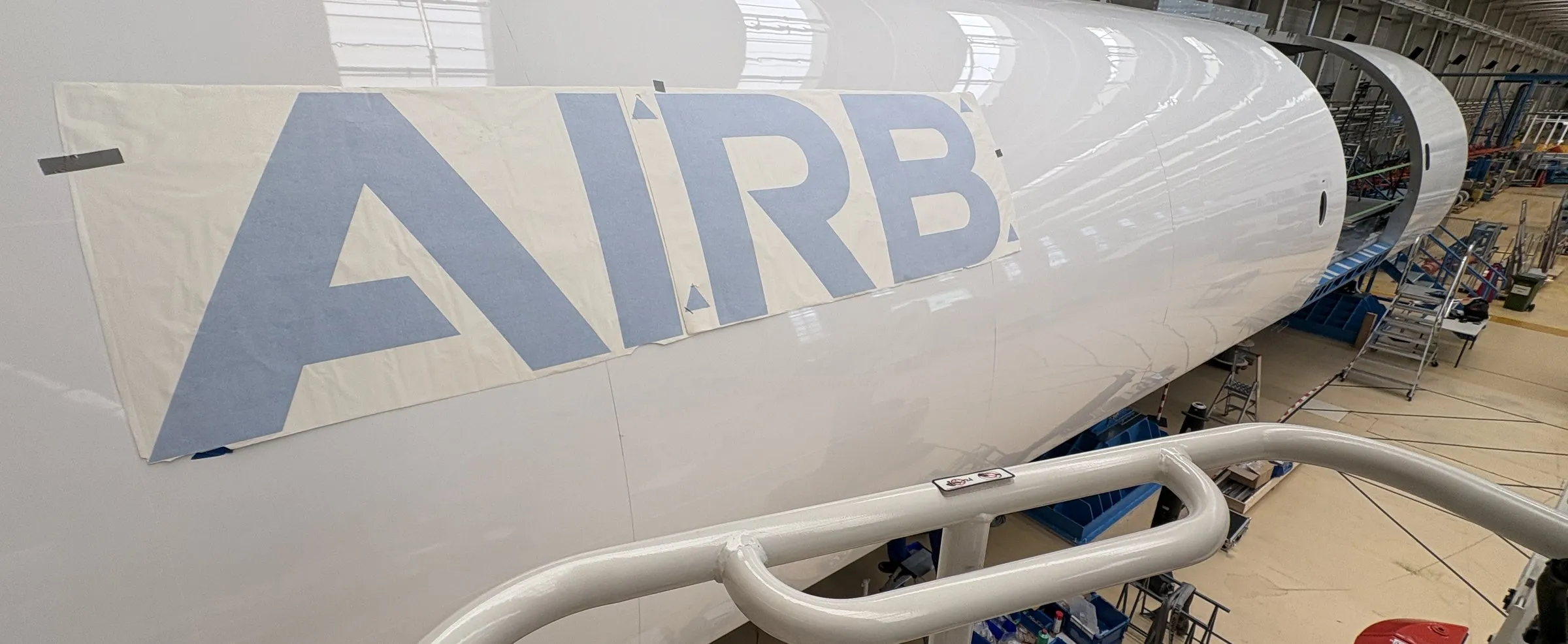 Airbus-Schriftzug wird mit Übertragungsfolie auf ein Rumpfsegment geklebt